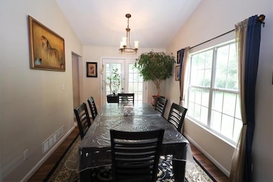 Dining space featuring vaulted ceiling, wood finished floors, baseboards, and a chandelier