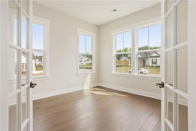 Empty room featuring hardwood / wood-style flooring, baseboards, and french doors