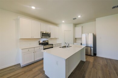 Kitchen featuring dark hardwood / wood-style flooring, backsplash, white cabinetry, and appliances with stainless steel finishes