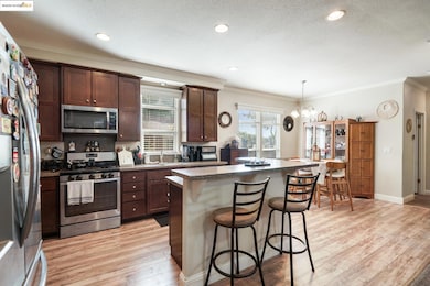 Kitchen featuring a breakfast bar, appliances with stainless steel finishes, ornamental molding, dark countertops, and light wood-style flooring