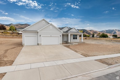View of front facade featuring board and batten siding, a mountain view, covered porch, concrete driveway, and an attached garage