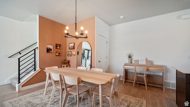 Dining space with stairway, a chandelier, light wood-type flooring, and arched walkways