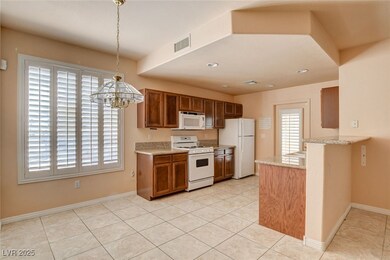Kitchen with white appliances, light tile patterned floors, brown cabinets, pendant lighting, and a chandelier