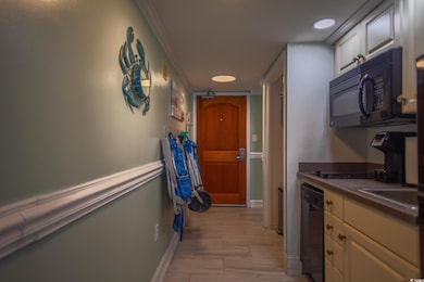 Kitchen featuring black appliances, dark countertops, white cabinetry, light wood-type flooring, and ornamental molding