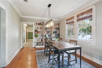 Dining room offers a built-in backdrop, beautiful lighting fixture, wood floors and more window light