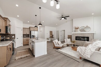 Kitchen featuring hanging light fixtures, open floor plan, appliances with stainless steel finishes, a premium fireplace, and decorative backsplash