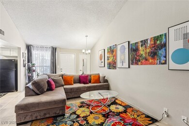 Living room with visible vents, lofted ceiling, light tile patterned flooring, a textured ceiling, and a notable chandelier