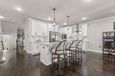 Kitchen featuring a kitchen bar, tasteful backsplash, stainless steel appliances, dark wood-style floors, and decorative light fixtures