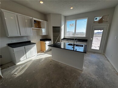 Kitchen with a center island with sink, white cabinets, a textured ceiling, unfinished concrete flooring, and recessed lighting