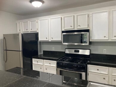 Kitchen with tile counters, white cabinetry, and 