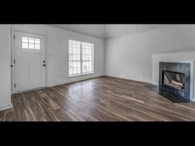 Foyer featuring wood finished floors, a tile fireplace, lofted ceiling, and baseboards