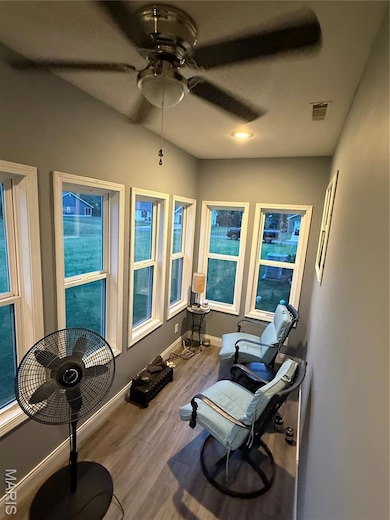 Sitting room with wood finished floors and a ceiling fan