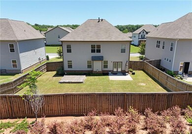 Back of house showing fully fenced yard with privacy fencing and patio area