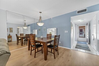 Dining room with floor to ceiling mirrors bounce natural light for an airy feeling.  Foyer to right and front door.