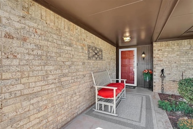 Doorway to property featuring a porch and brick siding