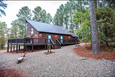 View of front of house featuring a deck, metal roof, log veneer siding, and view of wooded area