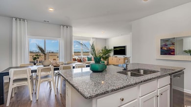 Kitchen with light stone counters, stainless steel dishwasher, sink, a center island with sink, and white cabinetry