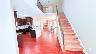 Kitchen featuring dark brown cabinets, tasteful backsplash, stainless steel appliances, dark wood-type flooring, and a towering ceiling