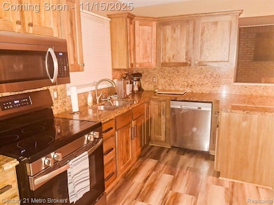 Kitchen featuring appliances with stainless steel finishes, backsplash, light wood-style flooring, light stone counters, and light brown cabinets