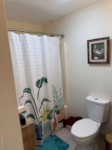 Bathroom with tile patterned floors and shower / bath combination with curtain