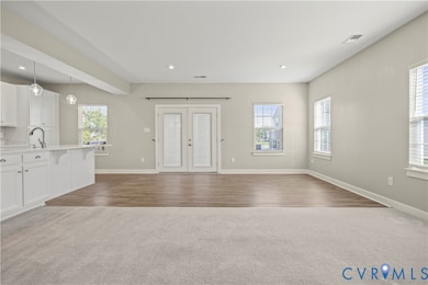 Foyer with dark colored carpet, french doors, healthy amount of natural light, recessed lighting, and dark wood finished floors