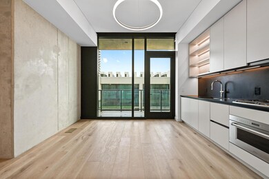 Kitchen with floor to ceiling windows, stainless steel oven, dark countertops, white cabinetry, and light wood-style flooring