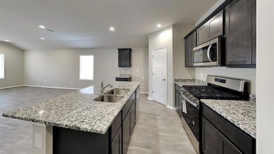 Kitchen with light stone countertops, sink, stainl