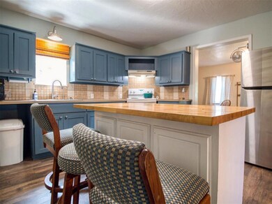 Kitchen with wooden counters, white range with electric cooktop, freestanding refrigerator, and blue cabinets
