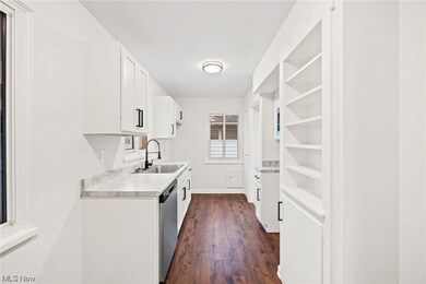 Kitchen with white cabinets, sink, dark wood-type flooring, and stainless steel dishwasher