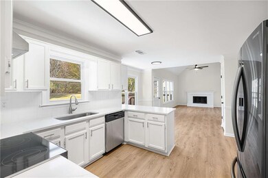 Kitchen with freestanding refrigerator, white cabinets, a peninsula, open floor plan, and crown molding