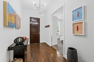 Entrance foyer featuring an inviting chandelier, dark hardwood / wood-style flooring, and ornamental molding