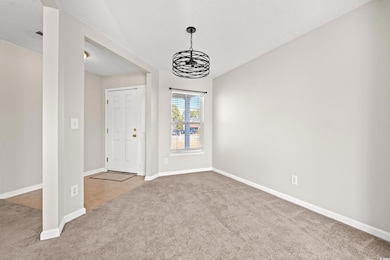 Carpeted entryway featuring a notable chandelier