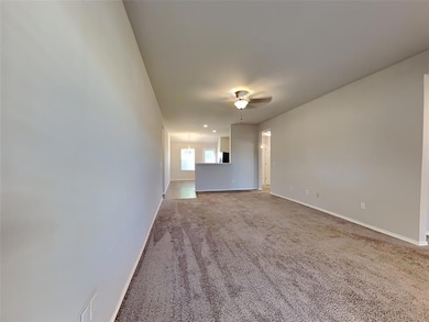 Unfurnished living room featuring a ceiling fan and carpet