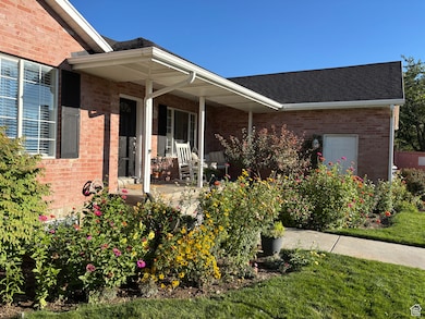 View of exterior entry featuring brick siding, a porch, and a shingled roof