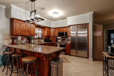 Kitchen with stainless steel appliances, a peninsula, crown molding, decorative backsplash, and brown cabinets