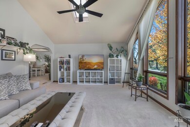 Carpeted living area with arched walkways, high vaulted ceiling, and a ceiling fan
