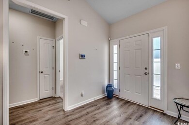 Foyer entrance featuring lofted ceiling and wood-t