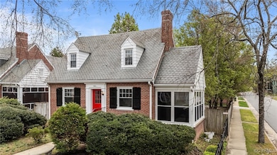 Cape cod house featuring a chimney, fence, and bri
