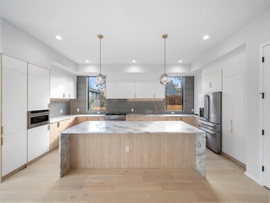 Kitchen featuring a center island, white cabinetry, light stone counters, decorative backsplash, and modern cabinets
