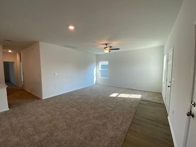Empty room with dark carpet, ceiling fan, recesse