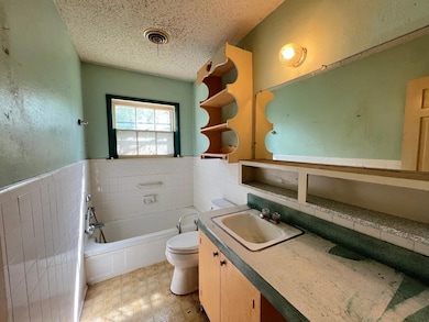 Bathroom with tile walls, a textured ceiling, a wa