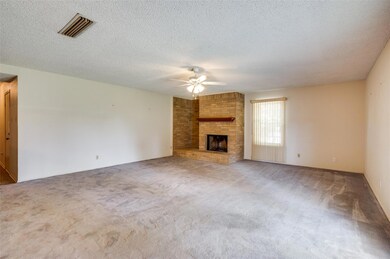 Unfurnished living room featuring a fireplace, carpet, a textured ceiling, and ceiling fan