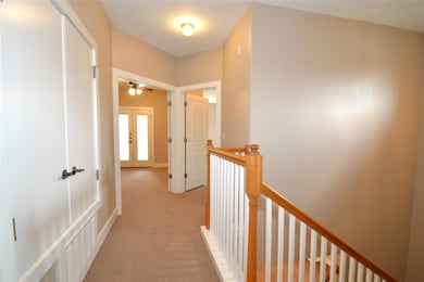 Hall with light colored carpet, an upstairs landi