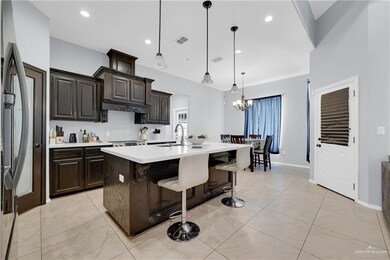 Kitchen with a notable chandelier, light countertops, a sink, a kitchen bar, and visible vents