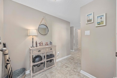 Hallway featuring a textured ceiling and light til