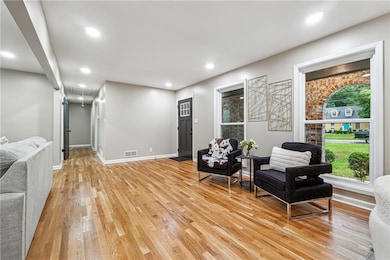 Sitting room with attic access, light wood-style floors, recessed lighting, and baseboards