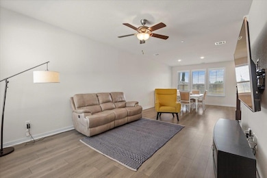 Living area featuring a ceiling fan and light wood finished floors
