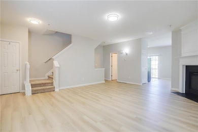 Unfurnished living room featuring light wood-style floors, stairway, and a fireplace with flush hearth