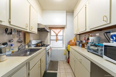 Kitchen with white appliances, light tile patterned flooring, under cabinet range hood, and light countertops