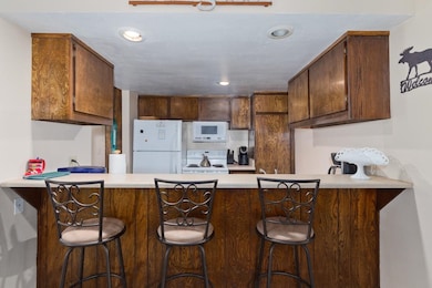 Kitchen with a peninsula, white appliances, light countertops, and recessed lighting